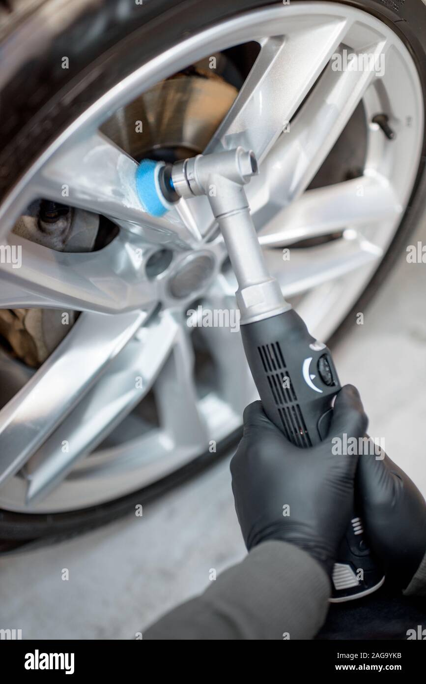 Guantes de protección del trabajador en el pulido del vehículo con disco amoladora profesional y cera de arañazos, close-up Foto de stock