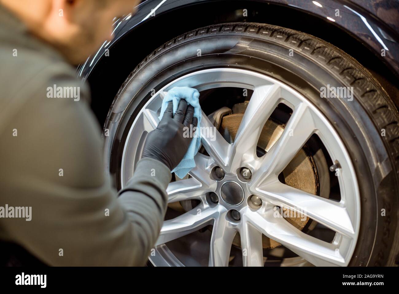 Guantes de protección del trabajador en el pulido del vehículo con disco amoladora profesional y cera de arañazos, close-up Foto de stock