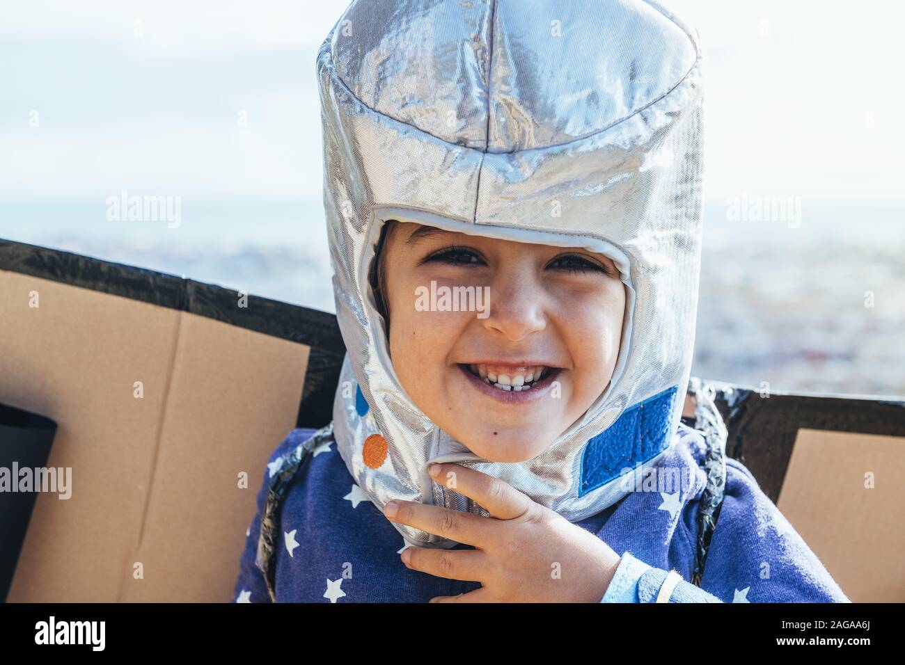 Retrato de una niña niño gracioso riendo naughty disfrazada como un  superhéroe con traje casero, cartón Avión alas y casco de astronauta, ima  Fotografía de stock - Alamy