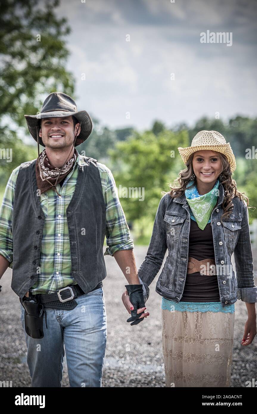 Tiro vertical de una pareja con un traje de vaquero y.. agarrando las manos  mientras sonríe a la cámara Fotografía de stock - Alamy