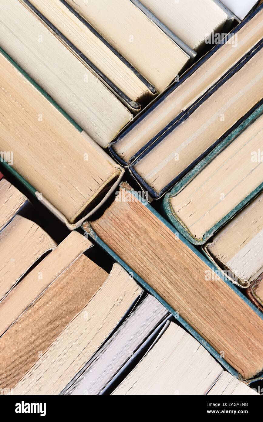 Un grupo grande de libros usados en orden aleatorio visto directamente desde encima, el formato vertical. Foto de stock