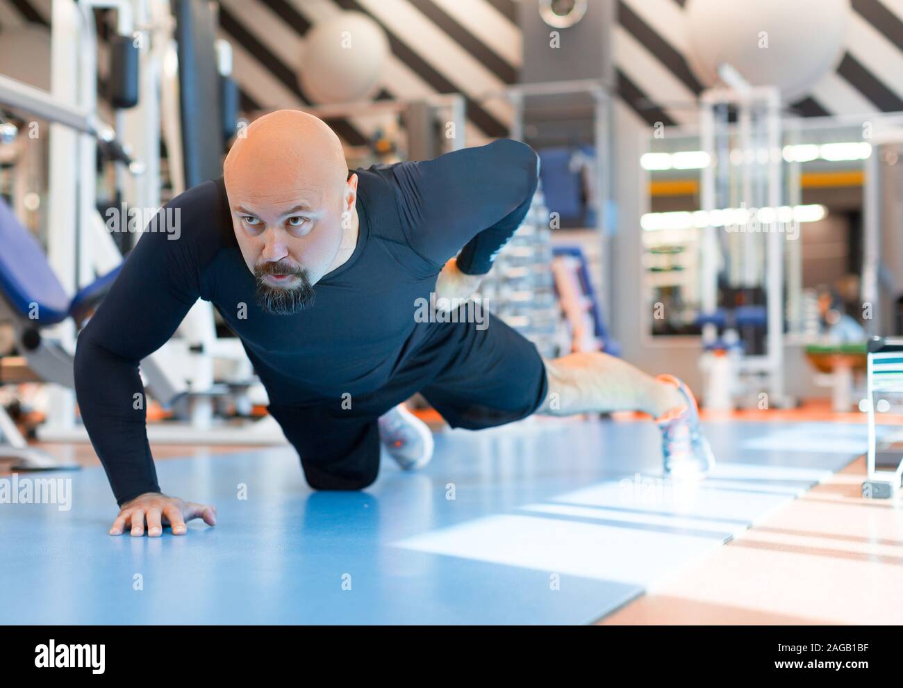 Hombre Barbado brutal haciendo flexiones con una mano de ejercicio en el gimnasio. Cierre vertical. Healty concepto de estilo de vida Foto de stock