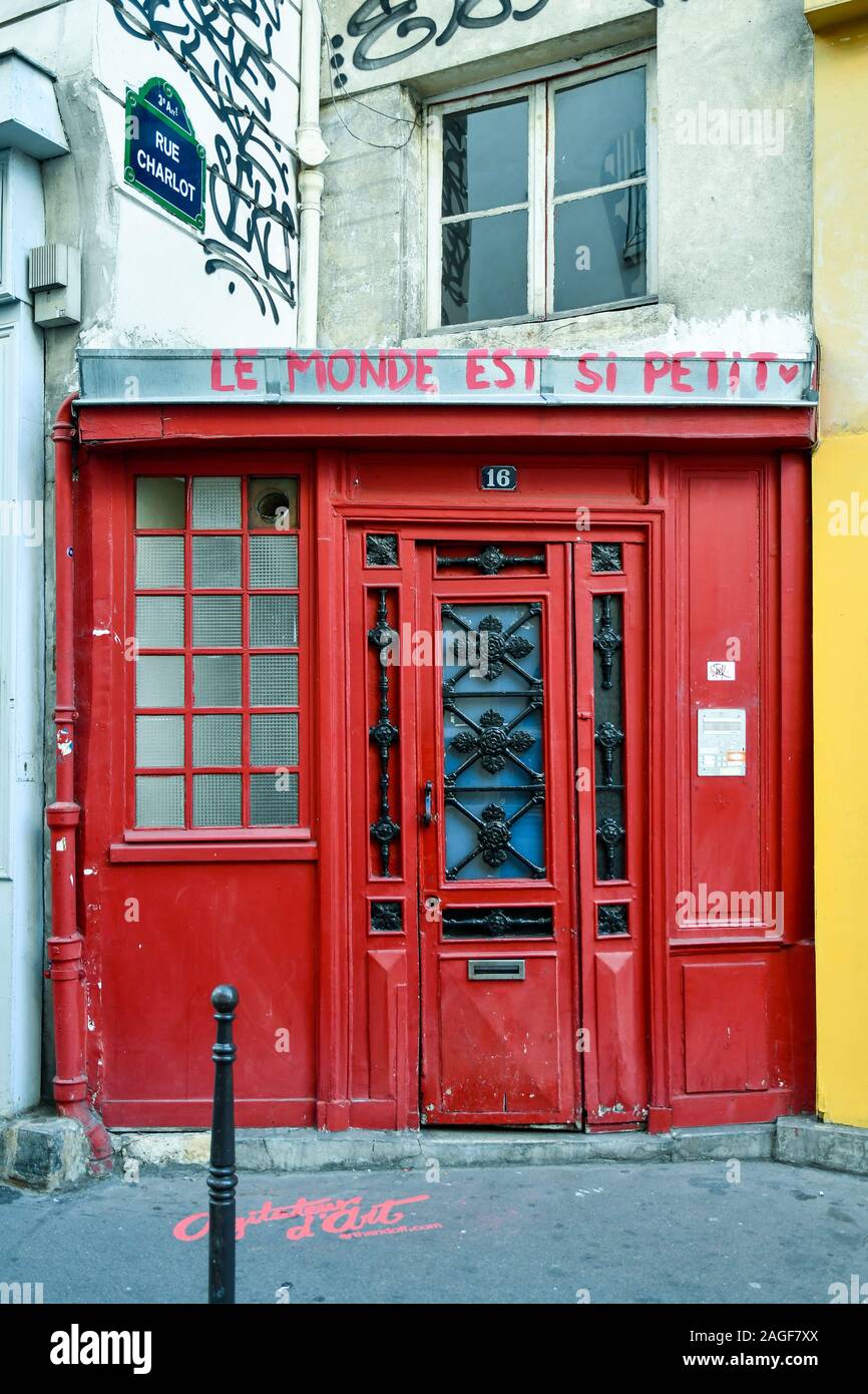 Un viejo, puerta de entrada de color rojo con graffiti en Rue Charlot, una calle en el distrito histórico de Marais, en el 3º arrondissement de París, Francia Foto de stock