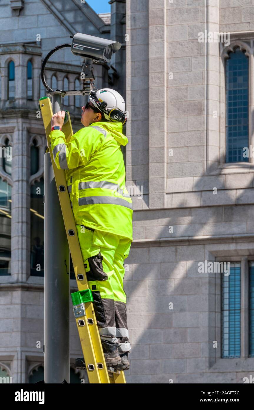 Ingeniero en una escalera trabajando en una cámara CCTV en el centro de la ciudad de Aberdeen. Foto de stock