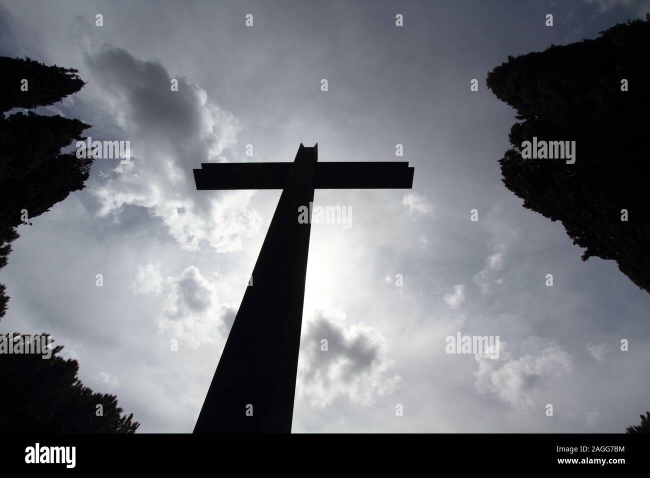 Fotografía conceptual de la muerte - silueta de una gran cruz con el cielo de fondo y los típicos setos del cementerio Foto de stock