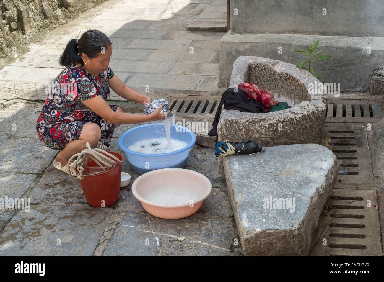 Una señora utiliza detergente en polvo para lavar ropa a mano cerca de un  pozo en Jianshui, Honghe, Yunnan, China Fotografía de stock - Alamy