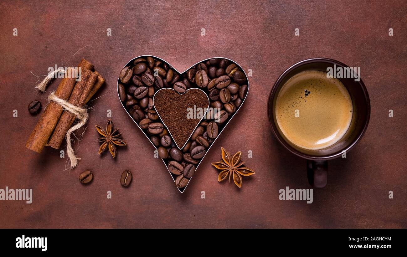 Composición con una taza de café, y la silueta en forma de corazón con los granos de café y café molido. Foto de stock