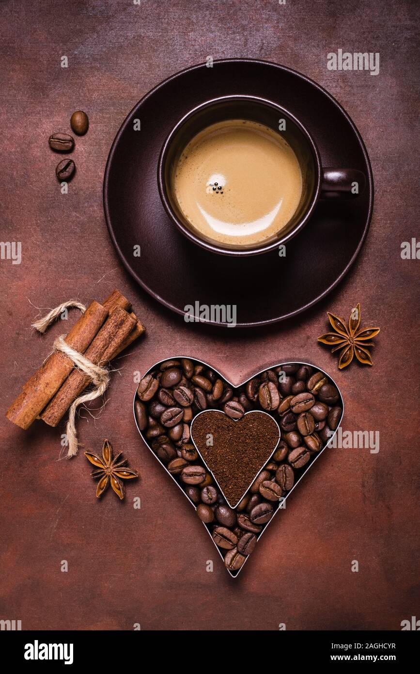 Composición con una taza de café, y la silueta en forma de corazón con los granos de café y café molido. Foto de stock