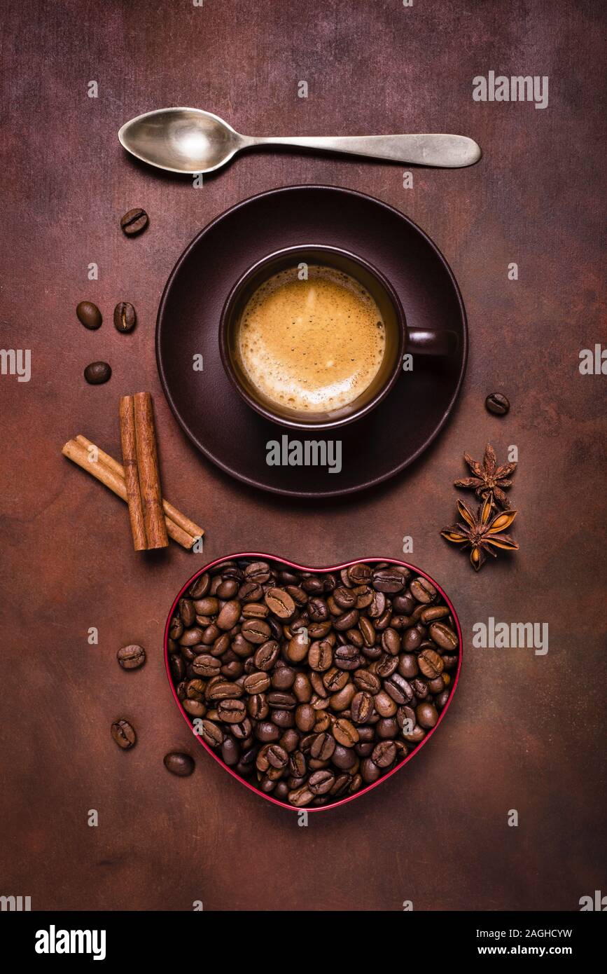Composición con una taza de café expreso y un recipiente en forma de corazón con granos de café. Foto de stock