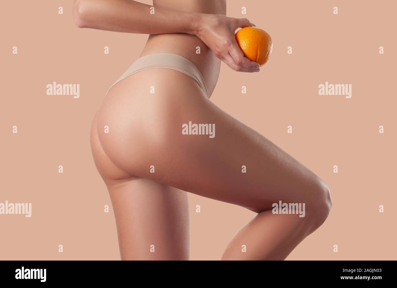 Mujer sosteniendo Slim naranja. Hembra perfectas nalgas sin celulitis.  Bella mujer's Butt en ropa interior. Cuidados del cuerpo y masajes anti  celulitis Fotografía de stock - Alamy