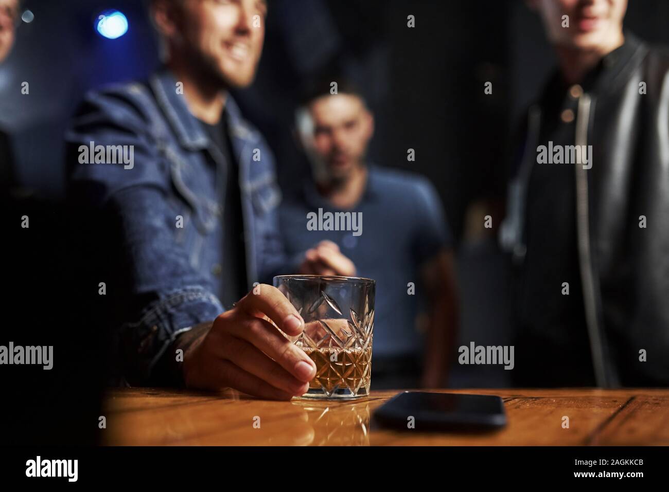 Se centró la foto. Los amigos en el bar. El hombre posee cristal con whiskey. Foto de stock