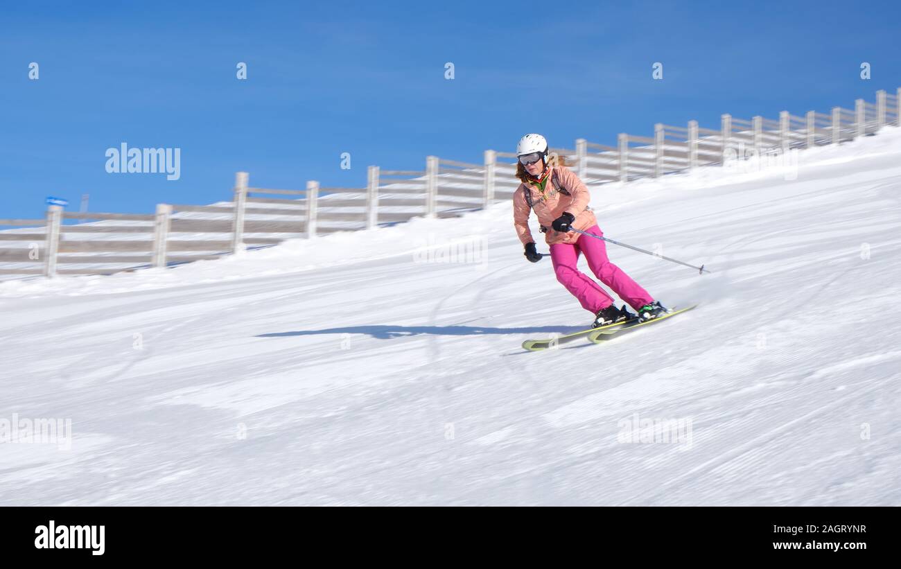 Mujer esquí en Sinaia resort en Rumania en un día soleado con perfecta nieve, sobre una pendiente de dificultad media (pista roja), en todos los esquís de montaña - panorámica sh Foto de stock