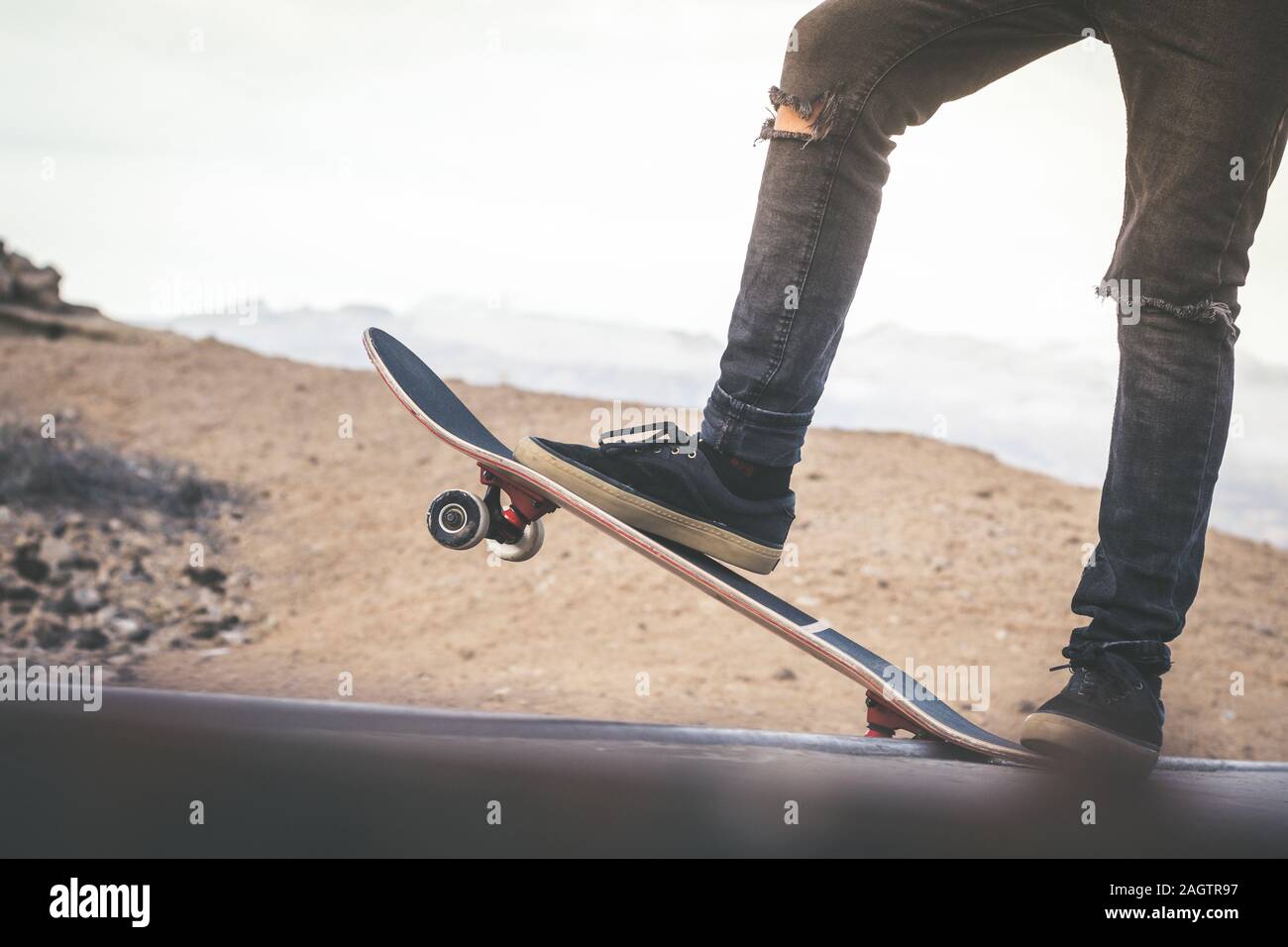 Vista de cerca de los pies del adolescente en un monopatín listo para iniciar un viaje en el half pipe. Skater comenzando saltos y trucos en el parque de skate. Let's go en Foto de stock