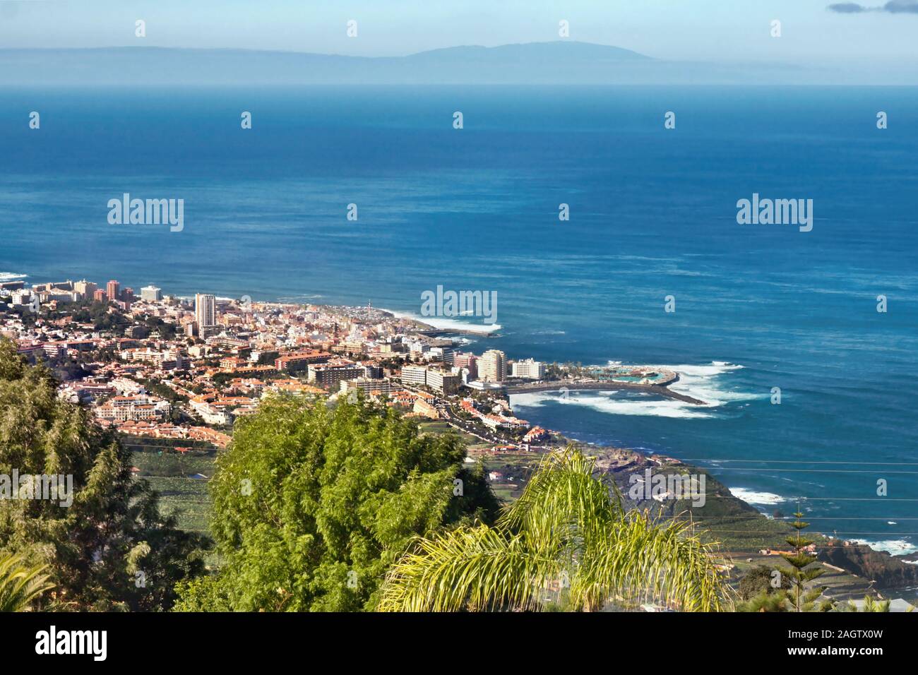 Vista sobre las copas de los árboles verdes de la costa norte y puerto de  la Cruz en la isla de Tenerife con el azul oscuro del Océano Atlántico y un  cielo