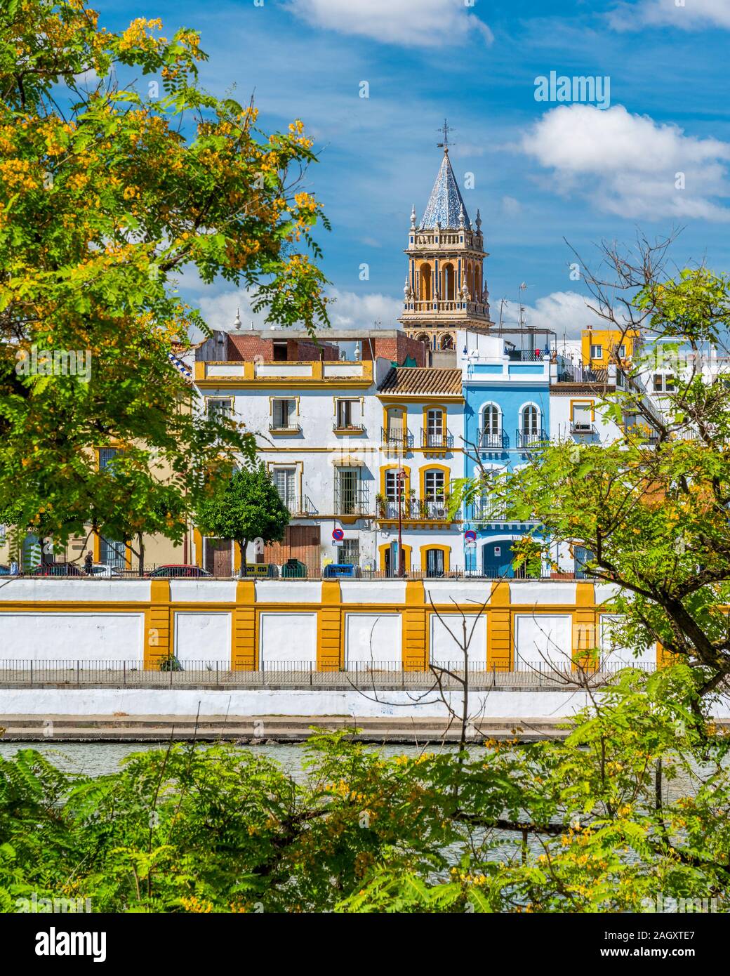 Vista colorida junto al río Guadalquivir en Sevilla, con la torre del campanario de la Real Parroquia de Señora Santa Ana. Andalucía, España. Foto de stock