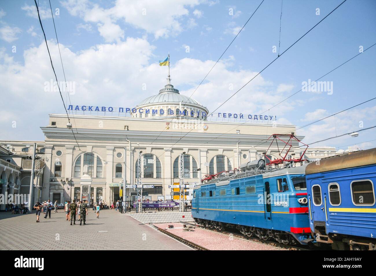 Odesa, Ucrania - Agosto 6, 2014: el edificio principal de la estación de tren de Odessa con un tren de pasajeros de los ferrocarriles (ukrzaliznytsia ucraniano) en el pl Foto de stock