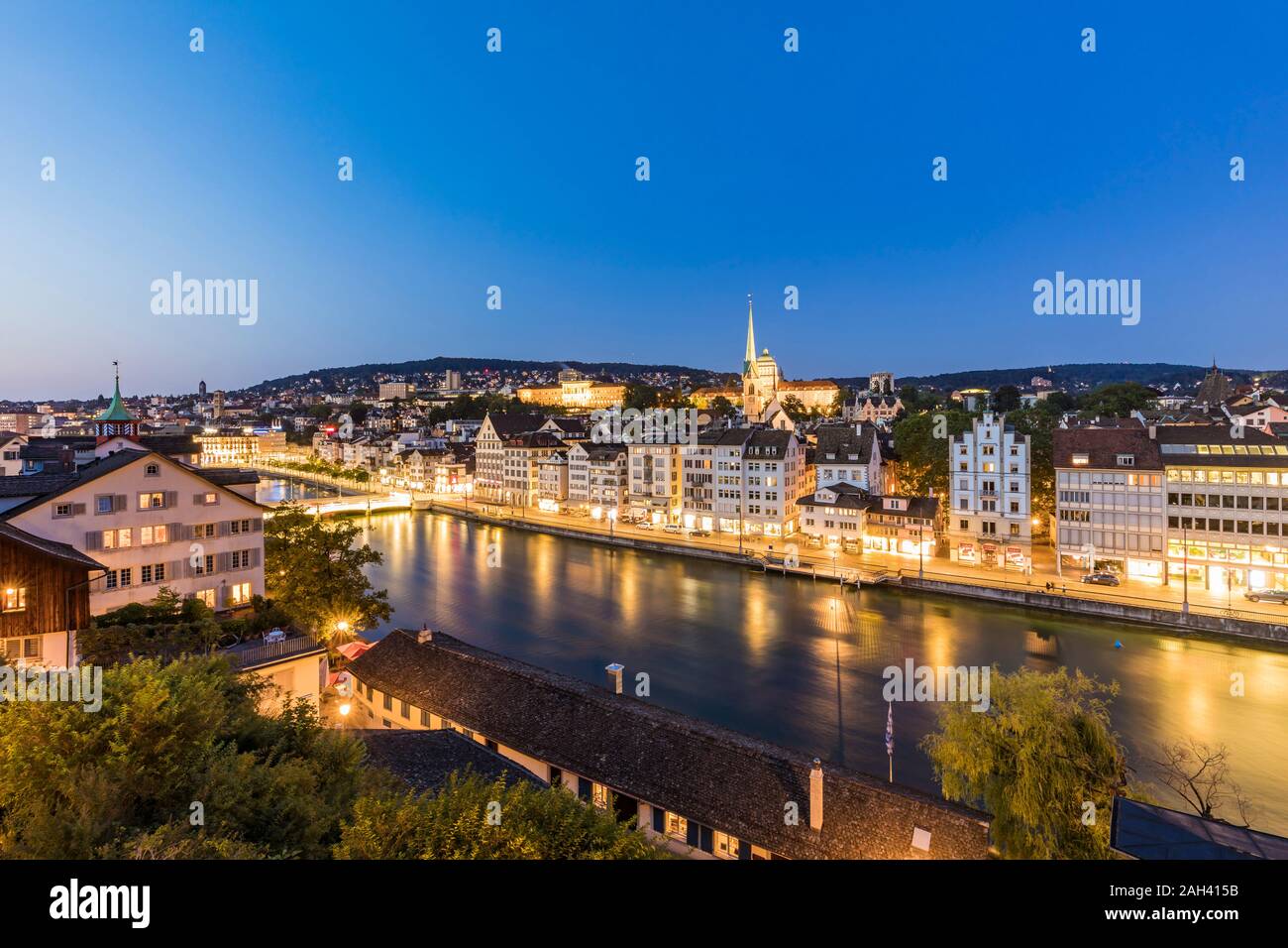 Suiza, en el cantón de Zurich, Zurich, el Río Limmat y el casco antiguo de edificios junto a la calle Limmatquai iluminada al atardecer Foto de stock