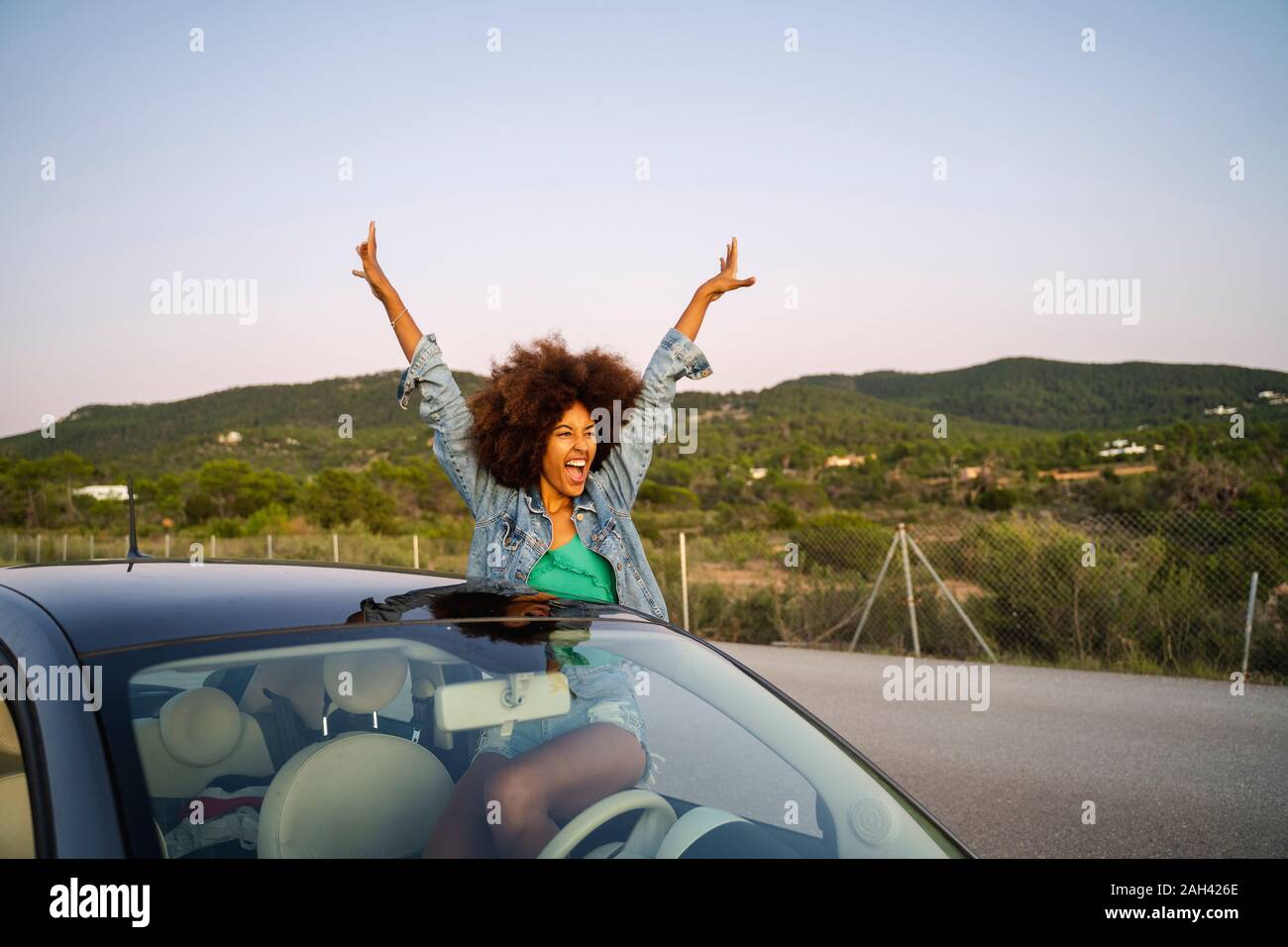 Mujer joven durante el viaje por carretera con brazos levantados Foto de stock