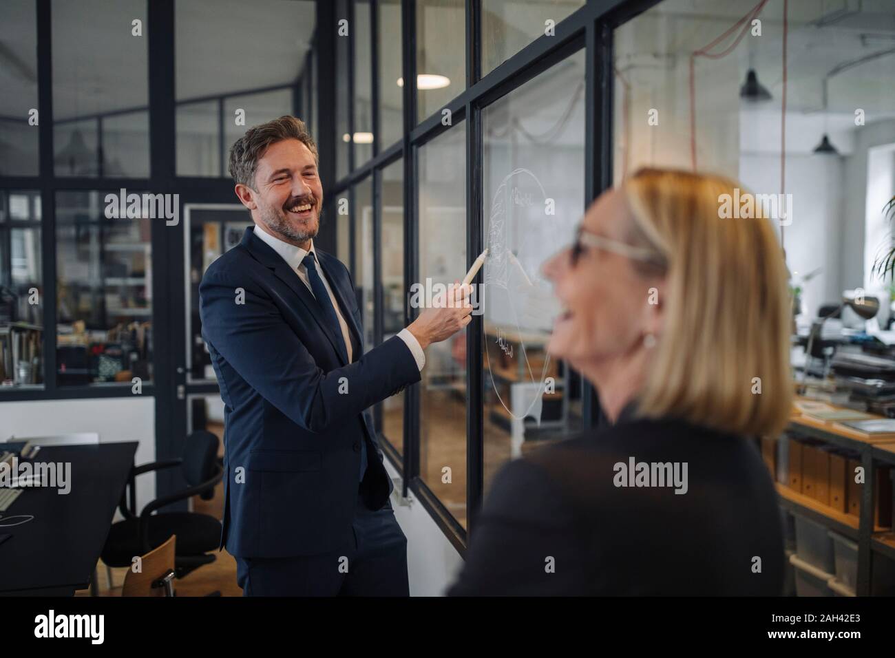 Empresario y empresaria mirando Dibujo en cristal en Office Foto de stock