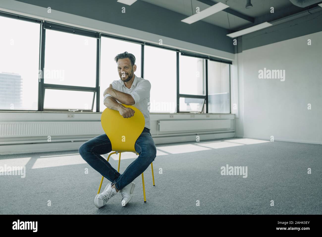 Retrato de confianza empresario maduro sentado en amarillo en silla de oficina vacía Foto de stock