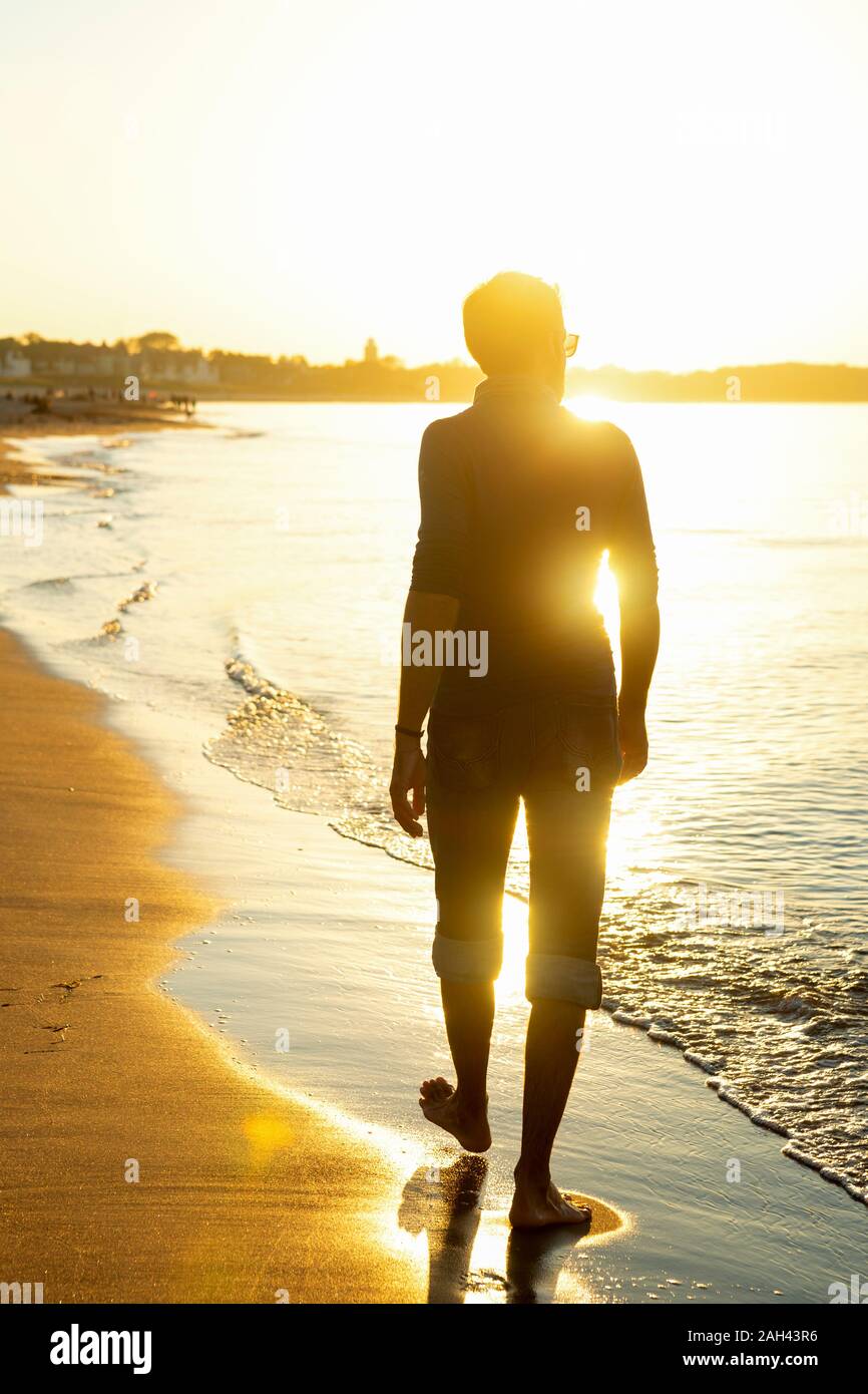 Hombre caminando por la playa al atardecer, Alemania Warnemuende Foto de stock