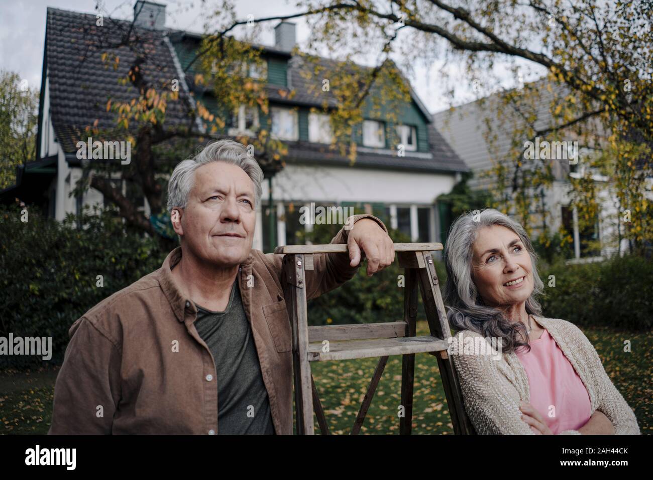 Las parejas ancianas con una escalera en el jardín de su casa Foto de stock
