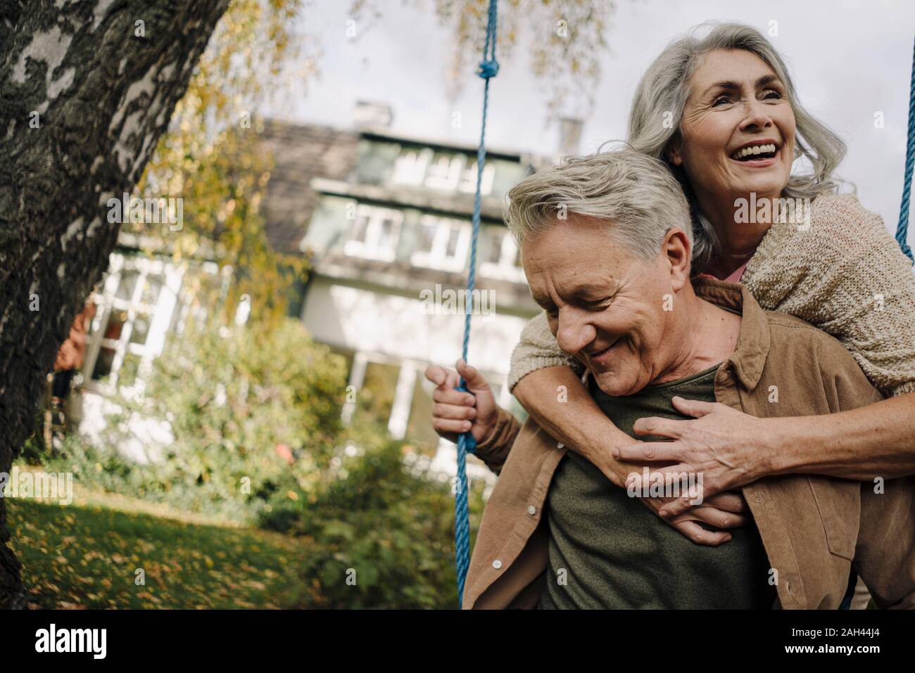 Mujer feliz abrazando hombre senior en un columpio en el jardín Foto de stock