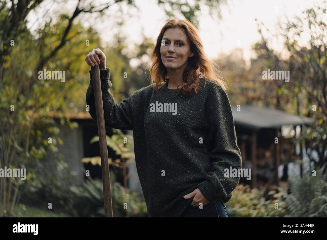 Mujer trabajando en su jardín, sosteniendo la pala Foto de stock