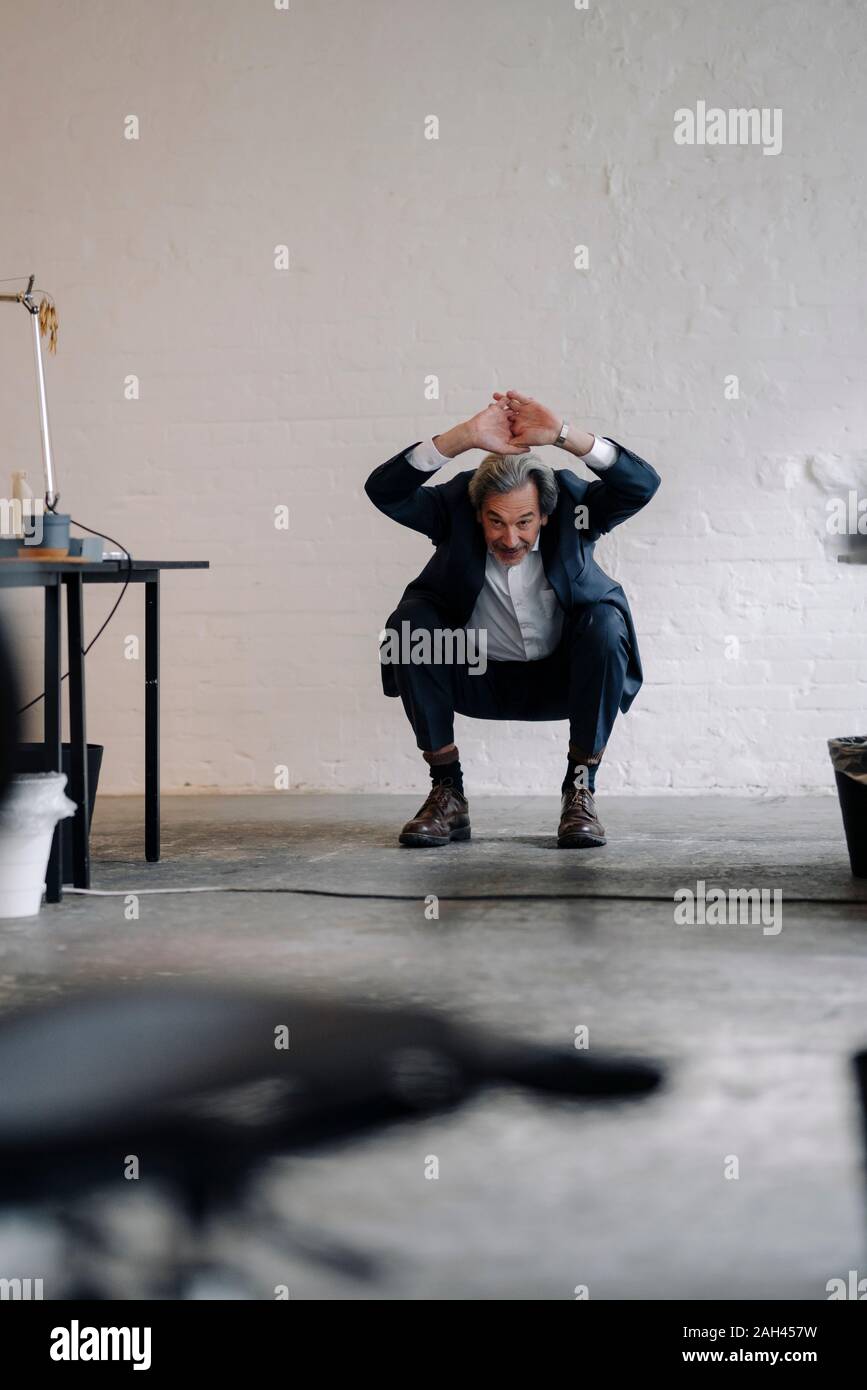 Empresario Senior haciendo gimnasia en la oficina Foto de stock