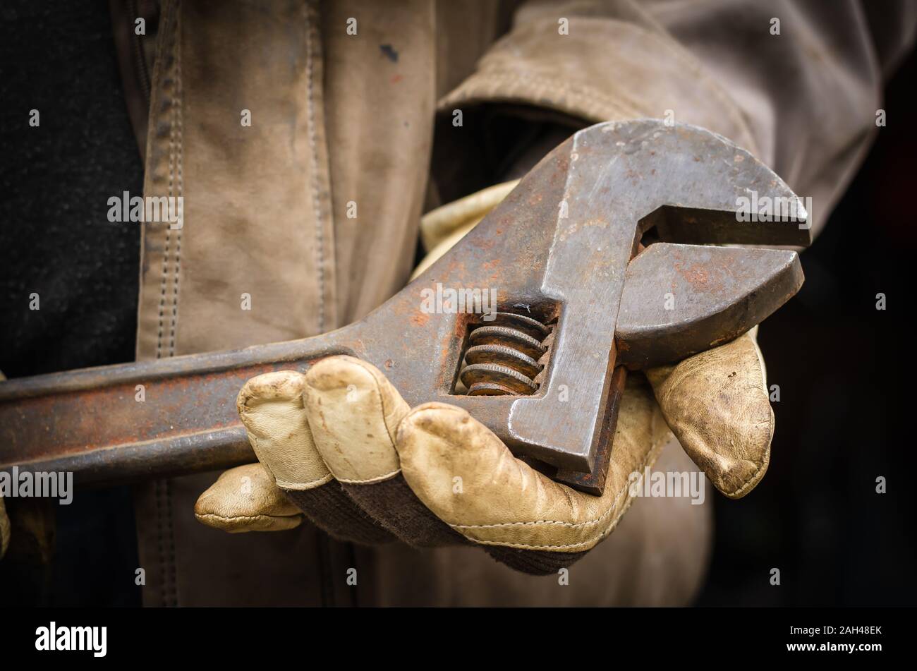 Rusty llave ajustable en manos masculinas. Mecánico de protección, guantes  de trabajo tiene una enorme llave. Close-up. Nivel del ojo dispara  Fotografía de stock - Alamy