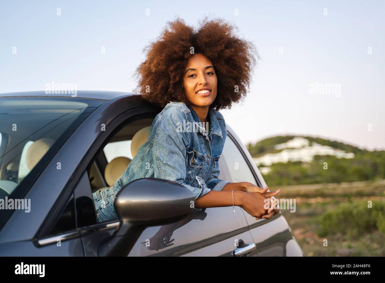 Mujer joven durante el viaje por carretera, asomarse a la ventana Foto de stock