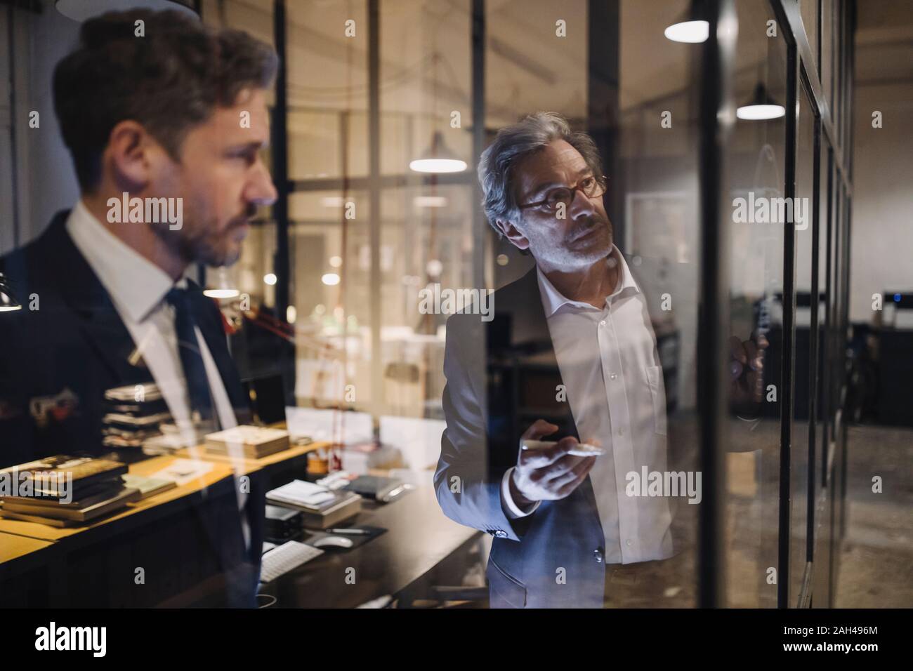 Dos hombres de negocios que trabajan en la elaboración de cristal en Office Foto de stock