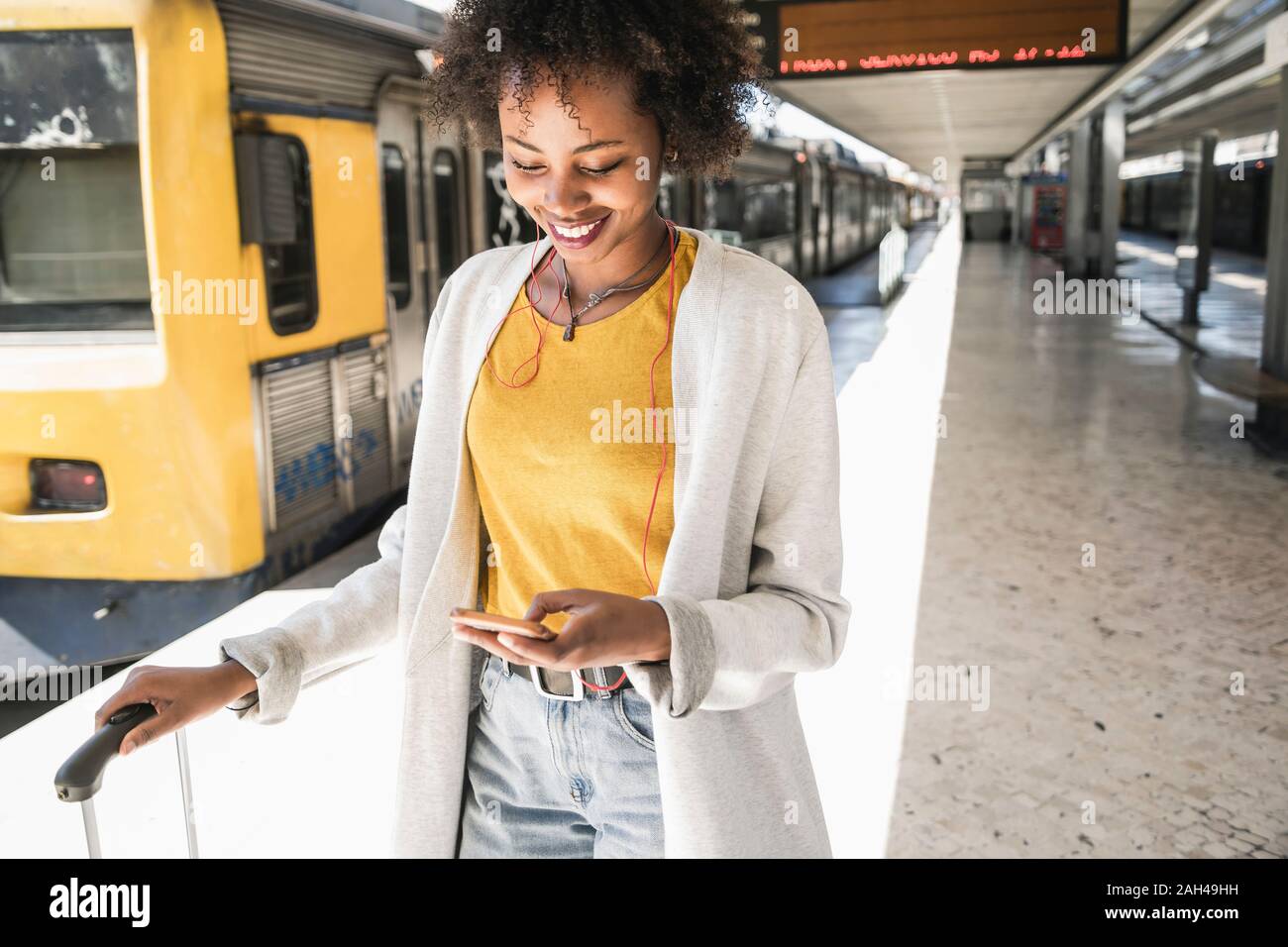 Mujer sonriente con auriculares y en la plataforma smartphone Foto de stock