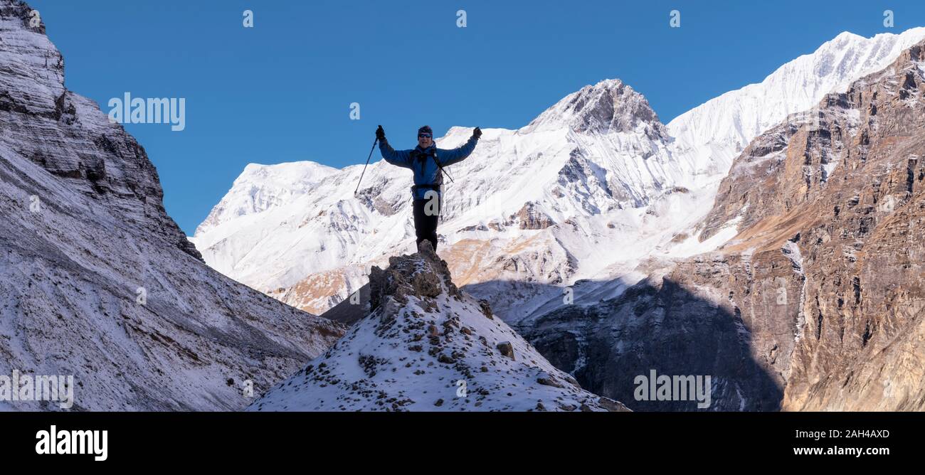 El Mountaineer vítores en la cima de una roca, Dhaulagiri Circuito Trek, Himalaya, Nepal Foto de stock