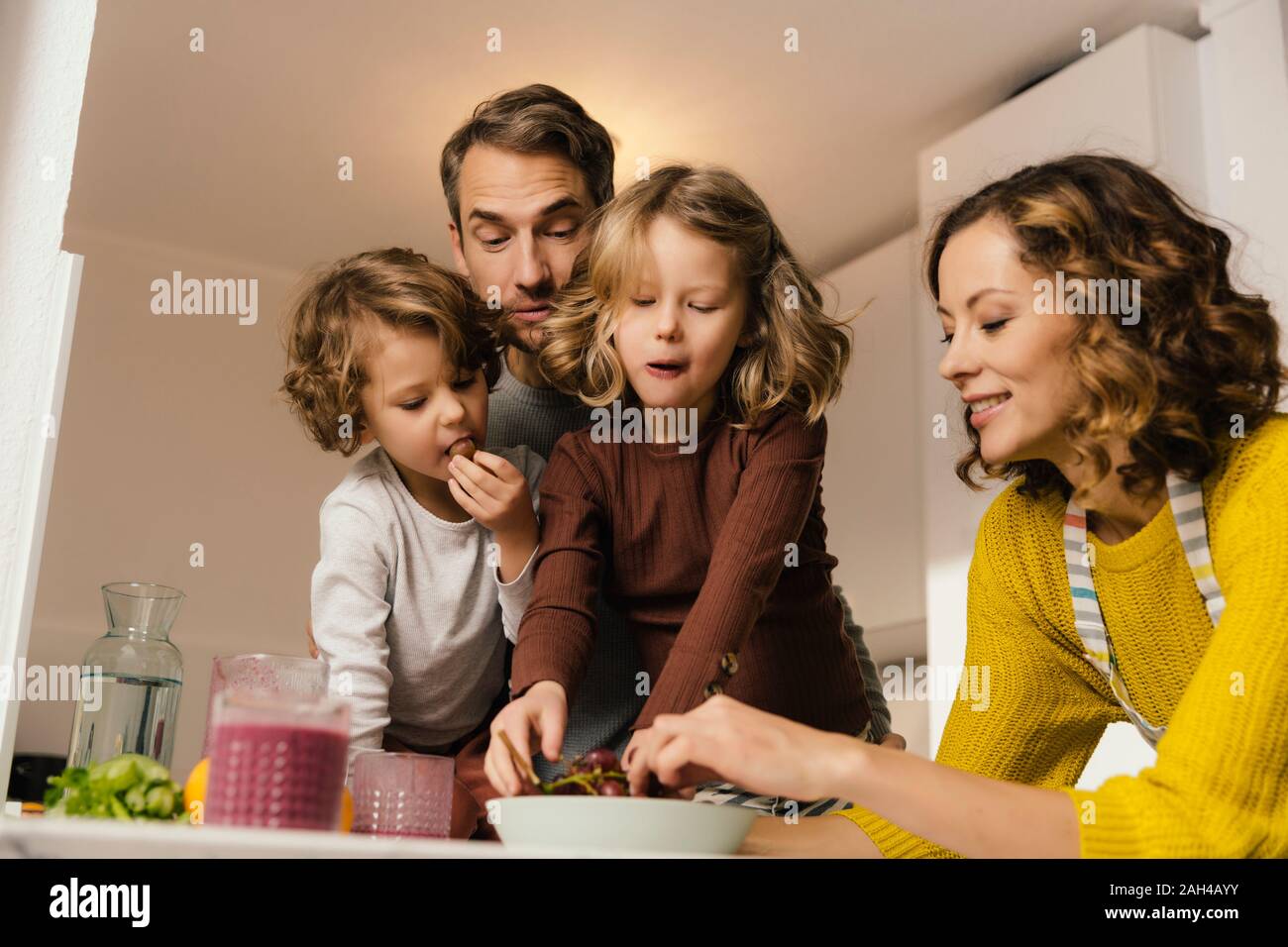 Familia comiendo uvas en la cocina Foto de stock