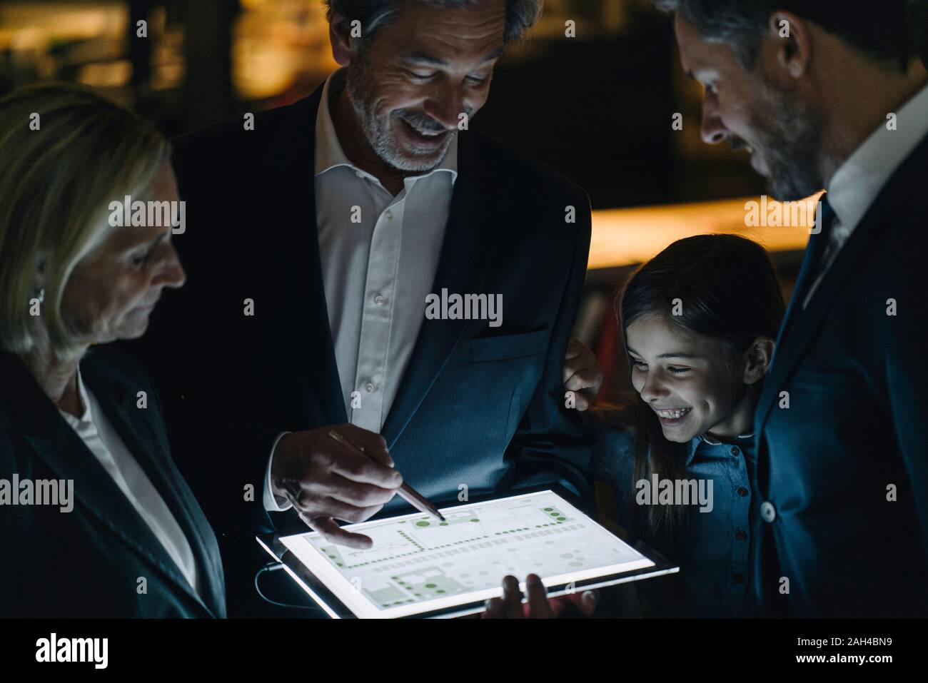 La gente de negocios y la muchacha mirando brillando tablet en Office Foto de stock