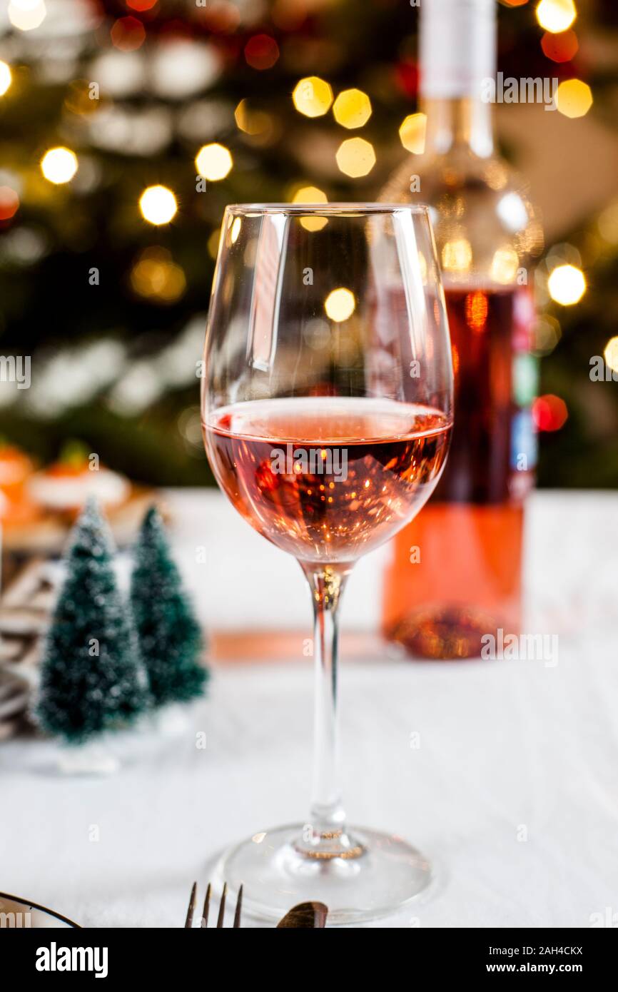 Copa de vino sonrosado delante de decoración navideña Foto de stock
