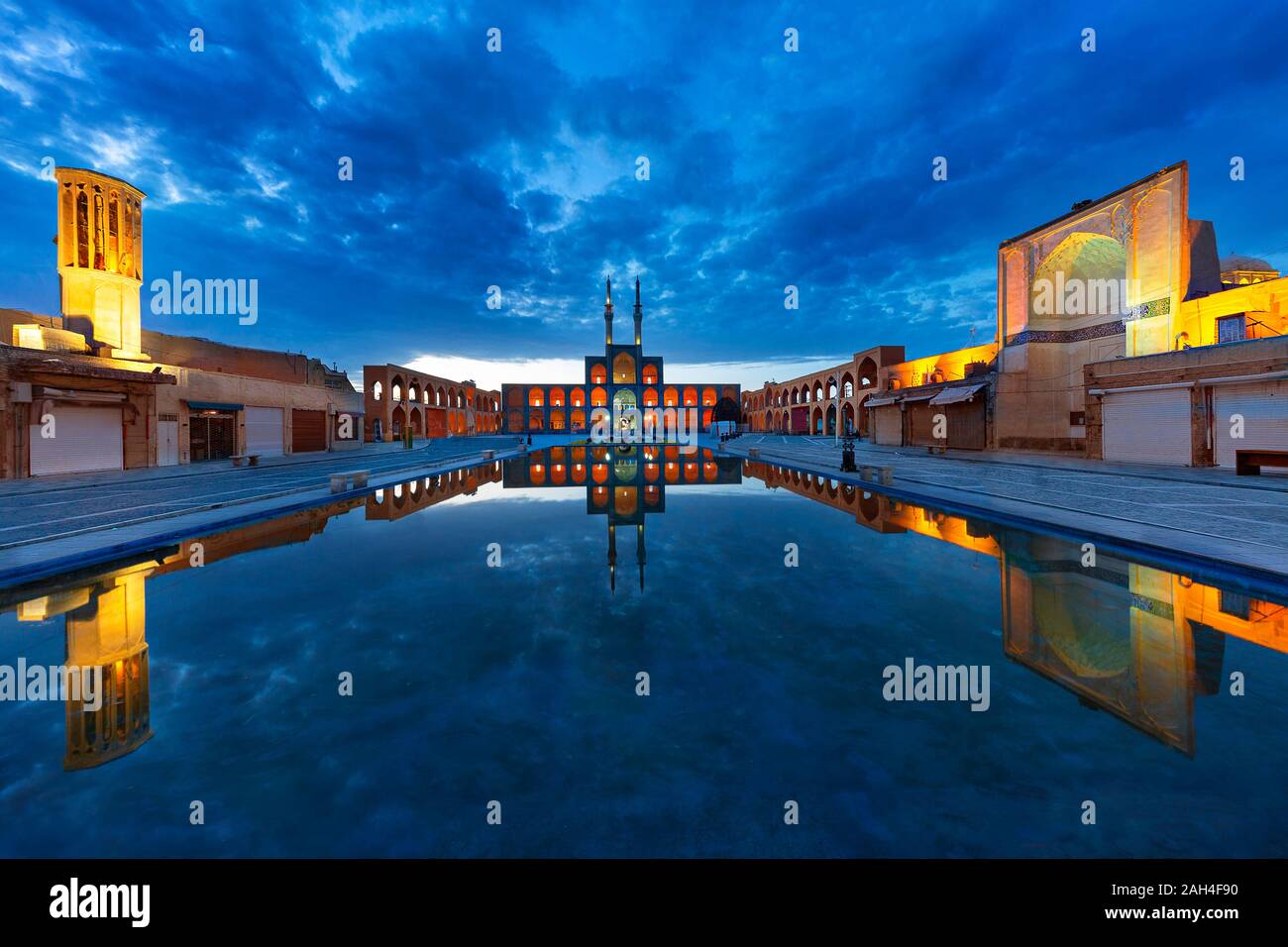 Amir Chakhmaq mezquita y su reflejo en la piscina, en la penumbra, en Yazd, Irán Foto de stock