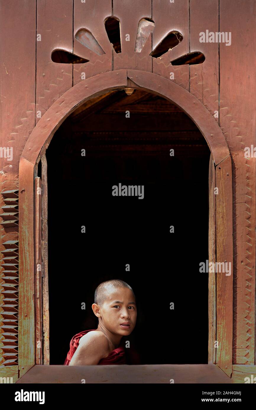 Joven monje mirando por la ventana del monasterio, en Lago Inle, Myanmar Foto de stock