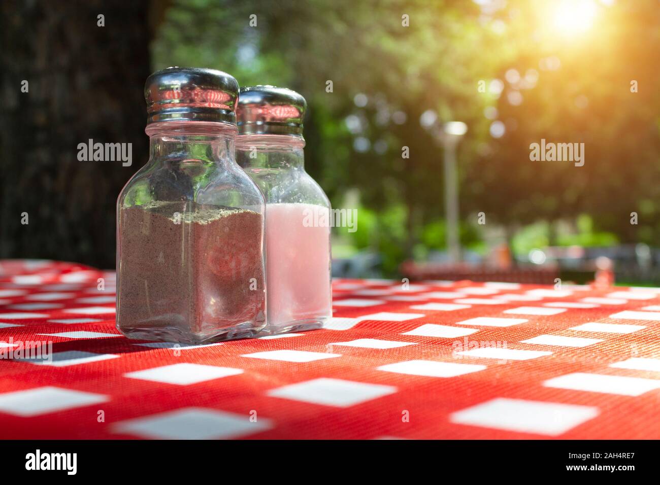 Salero y pimentero de mantel de picnic con sol de fondo. Foto de stock