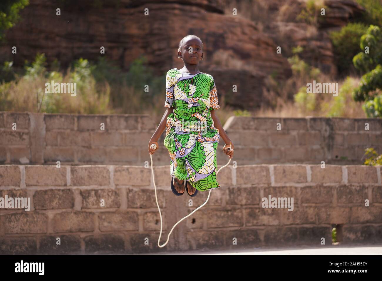 Pequeña muchacha africana con un hermoso vestido verde concentrándose en su omitiendo el rendimiento Foto de stock