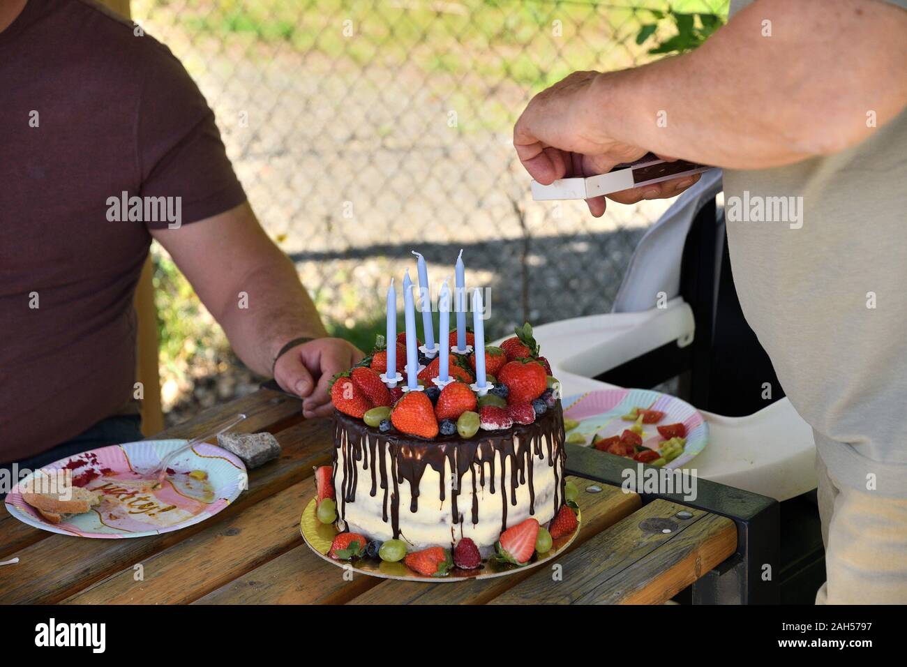Hombre Ilumina Las Velas En El Pastel De Cumpleanos Decorado Con Chocolate Y Fresas Fotografia De Stock Alamy