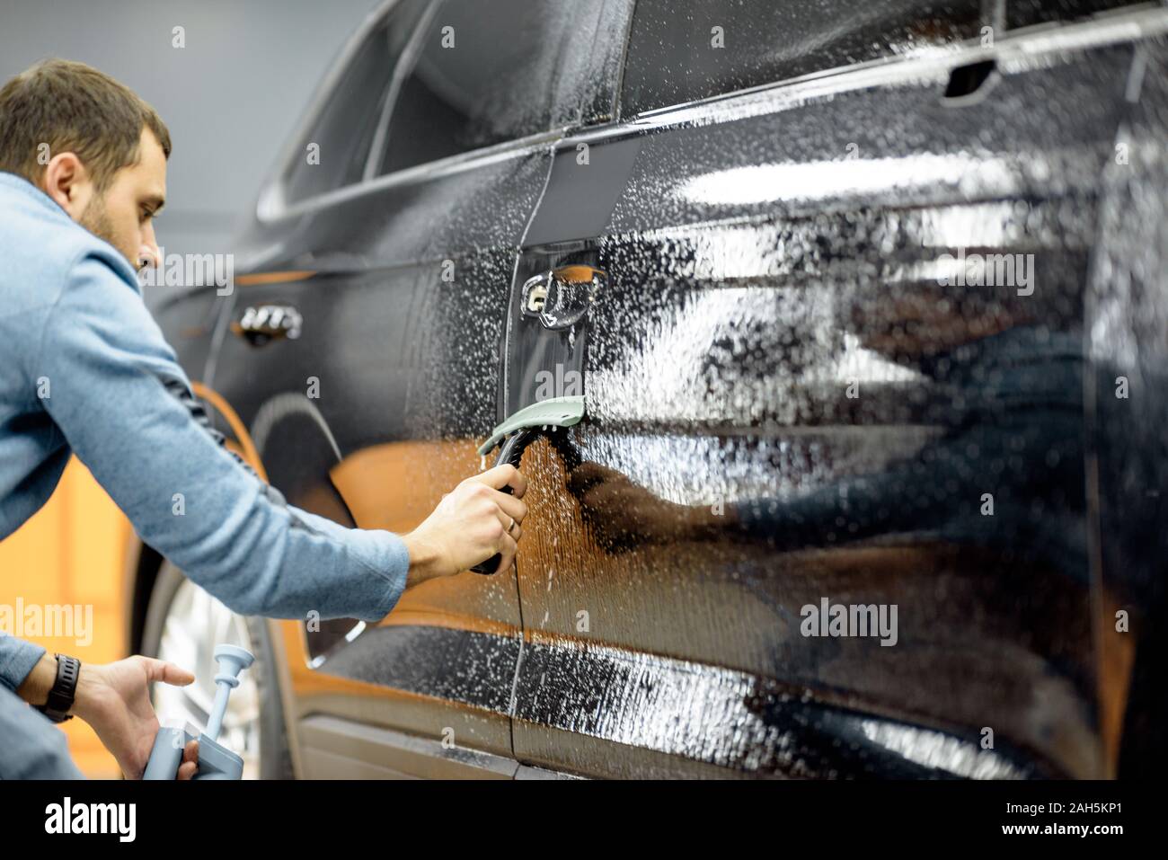 Servicio de coche trabajador extrayendo agua de la carrocería del coche con  un raspador, antes de antigravilla película aplican en el detalle del  vehículo Fotografía de stock - Alamy