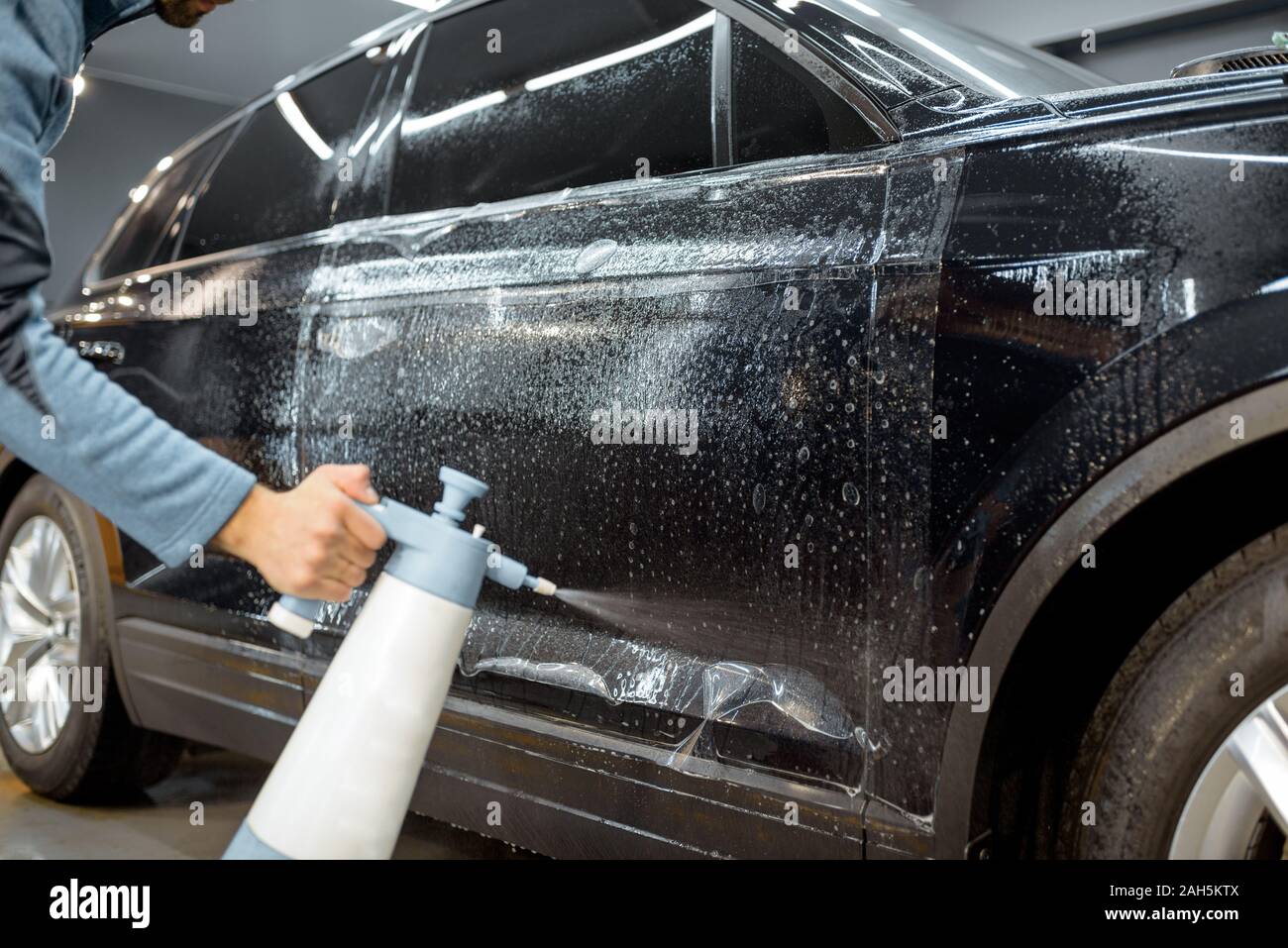 Servicio de coche trabajador salpicaduras de agua sobre la carrocería del  coche, la humectación antes de antigravilla película aplican en el detalle  del vehículo Fotografía de stock - Alamy