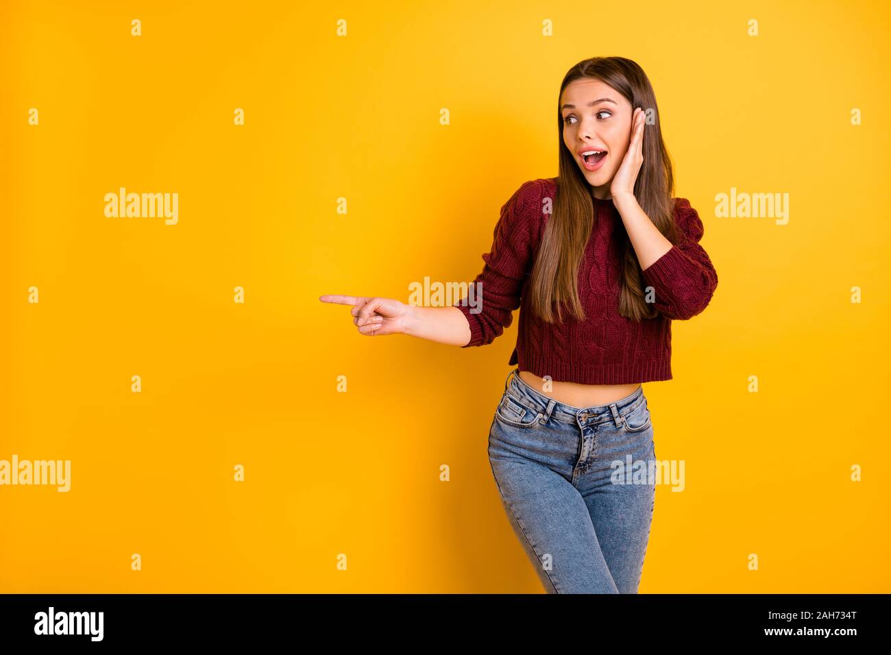 Retrato de dama asombrado buscando punto lateral de perfil en anuncios con  su dedo índice, desgaste granate suéter pantalones vaqueros aislado sobre  fondo amarillo Fotografía de stock - Alamy