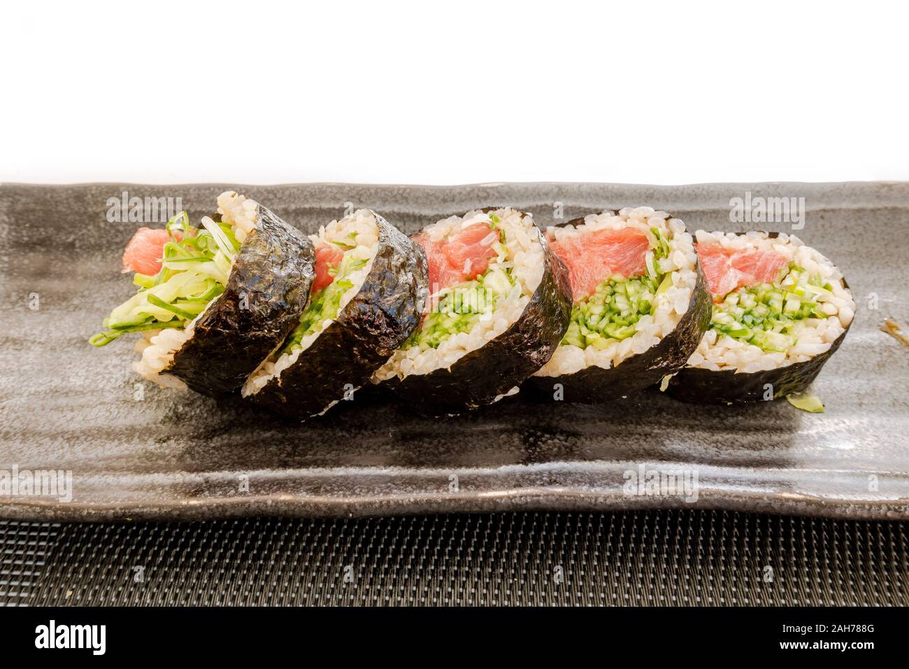 5 rollos de maki sushi envueltos con algas marinas en una placa. Foto de stock