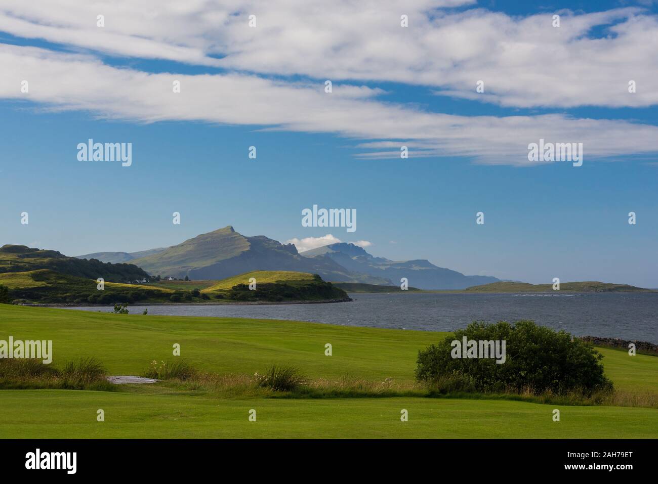 Paisaje tranquilo e icónico de la isla de Skye escocesa, con un prado verde en primer plano y montañas distantes en el fondo Foto de stock