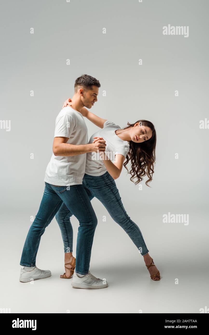 Bailarines en camisetas y jeans bailar Bachata sobre fondo gris Fotografía  de stock - Alamy