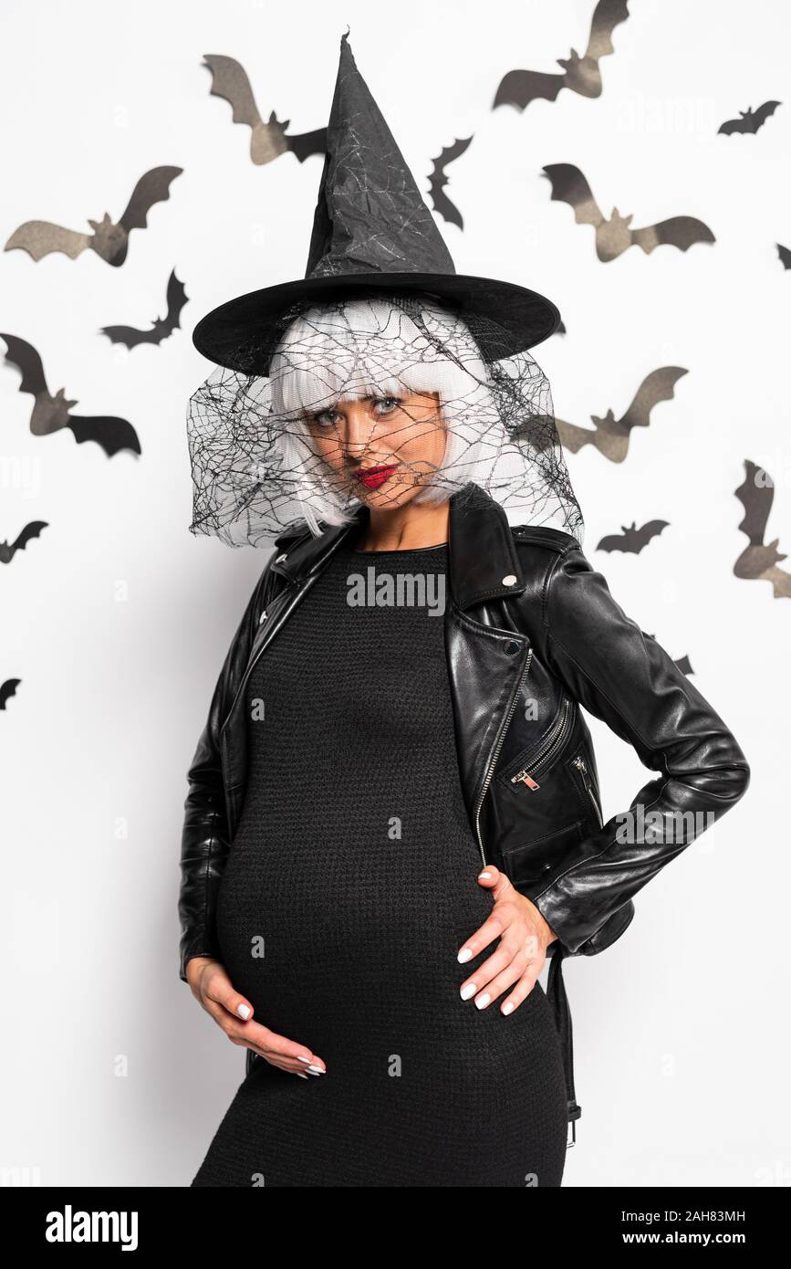 Mujer embarazada de bruja sombrero y peluca mirando a la cámara en Halloween  Fotografía de stock - Alamy