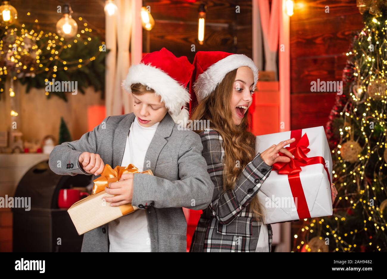 Feliz Navidad y Feliz Navidad. intercambio de regalos en el árbol de navidad  decorado. Año nuevo 2020. Familia cariñosa con regalos en la habitación. El  hermano y la hermana en santa hat.